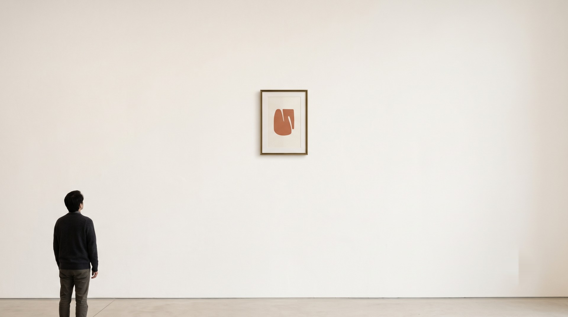 Grande parete bianca di galleria con un piccolo quadro incorniciato e una persona che lo osserva